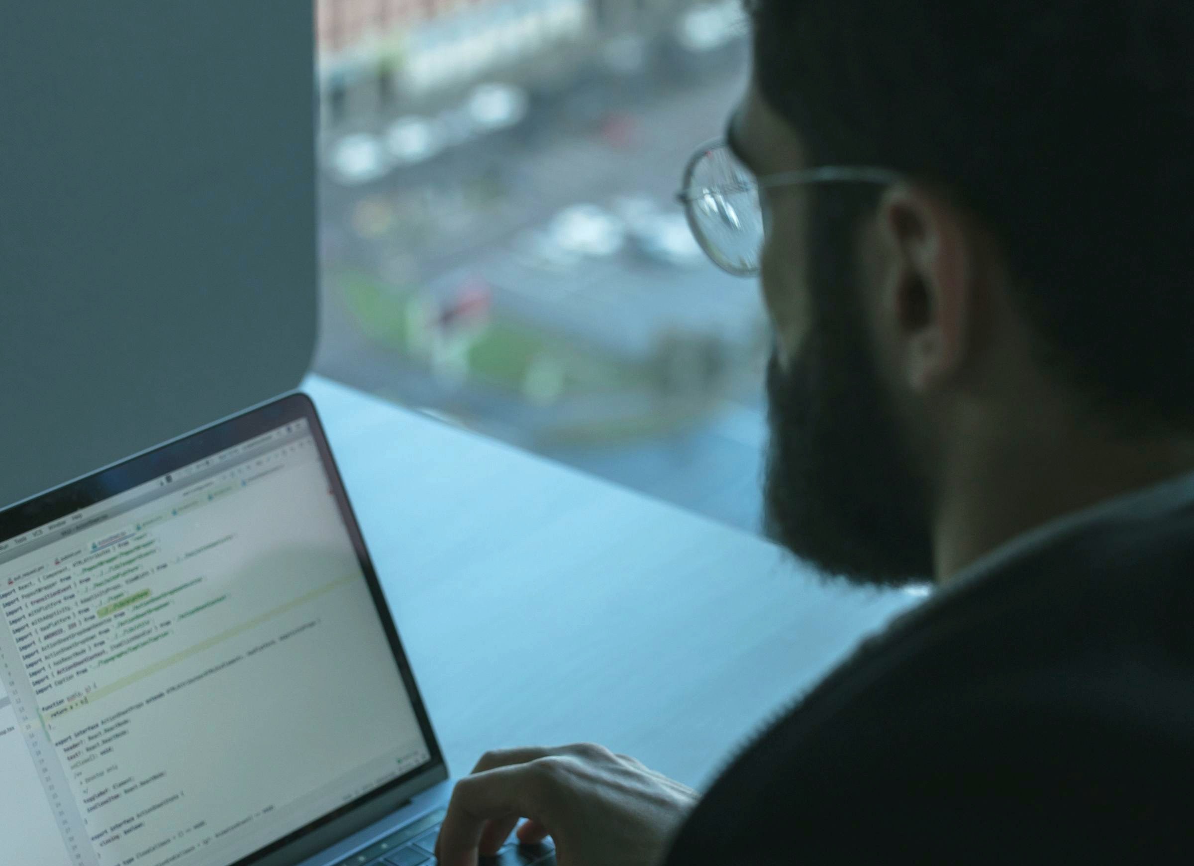Developer at a laptop mid-project, custom code open on screen